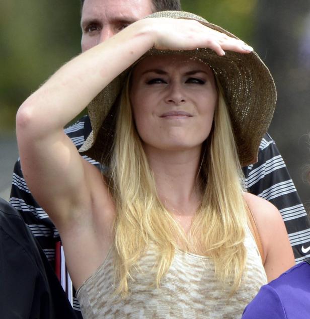 Eine blonde Frau mit Hut schirmt ihre Augen vor der Sonne ab.