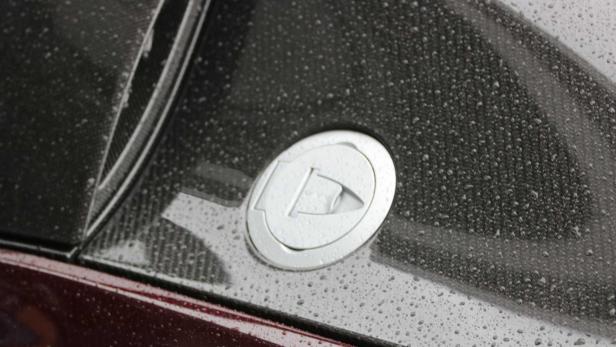 Ein silberner Tankdeckel an einem Auto im Regen.