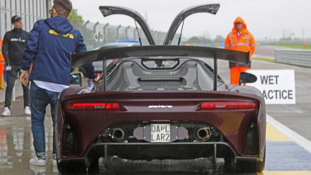 Ein Dallara-Sportwagen mit geöffneten Flügeltüren steht auf einer nassen Rennstrecke.