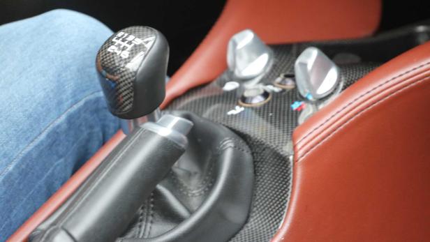 Innenraum eines Autos mit Schaltknüppel und braunen Ledersitzen.