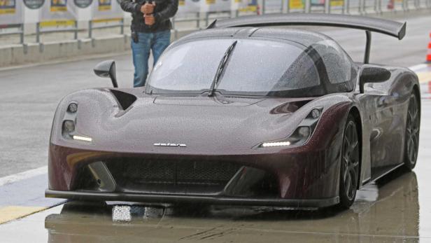 Ein dunkelroter Elara Sportwagen steht im Regen auf einer Rennstrecke.