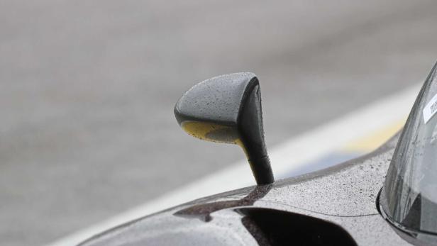 Ein Außenspiegel eines Autos ist mit Regentropfen bedeckt.