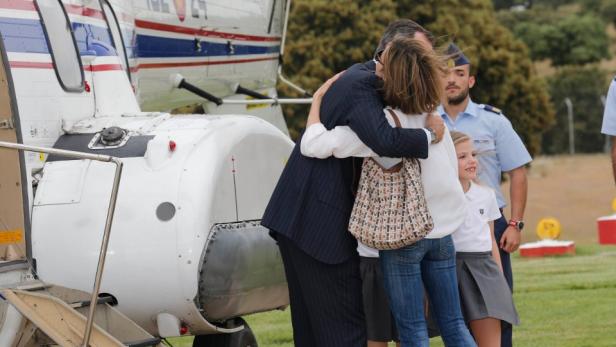 König Felipe umarmt Königin Letizia und Infantin Sofía vor einem Hubschrauber.