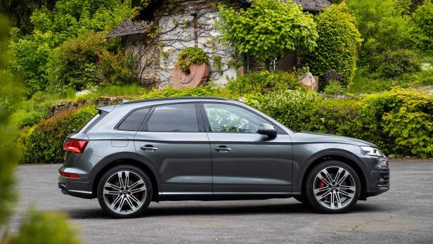 Ein grauer Audi Q5 steht vor einem mit Efeu bewachsenen Haus.