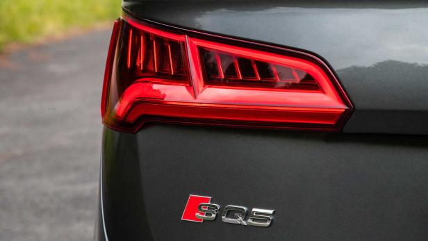 Nahaufnahme des Rücklichts und des SQ5-Emblems eines grauen Audi SQ5.