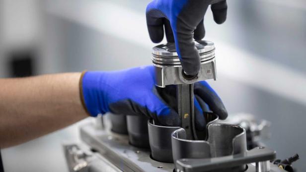 Ein Mechaniker montiert einen Kolben in einem Motorblock.