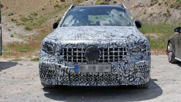 Ein Prototyp eines Mercedes-Benz SUV mit Tarnmuster auf einer Schotterstraße.