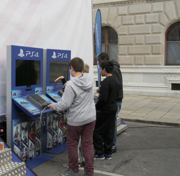 Eine Gruppe von Jugendlichen spielt an zwei PlayStation 4-Konsolen.