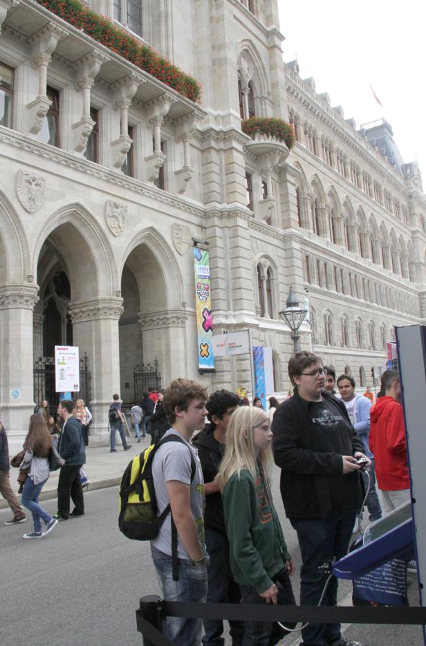 Menschen spielen vor dem Wiener Rathaus an Spielkonsolen der Game City.