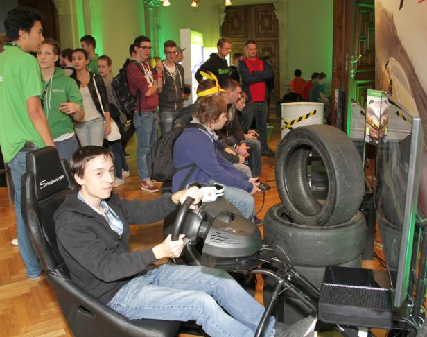 Ein junger Mann spielt ein Rennspiel an einem Simulator mit Lenkrad und Reifen.