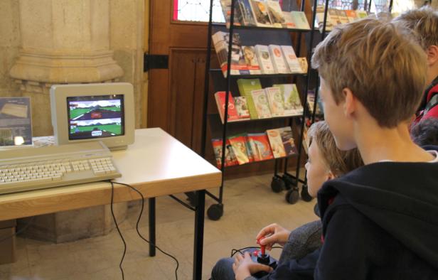 Zwei Jungen spielen ein Rennspiel auf einem alten Computer mit Joystick.
