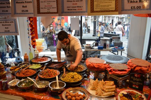Ein Mann bereitet an einem Marktstand indische Speisen zu.