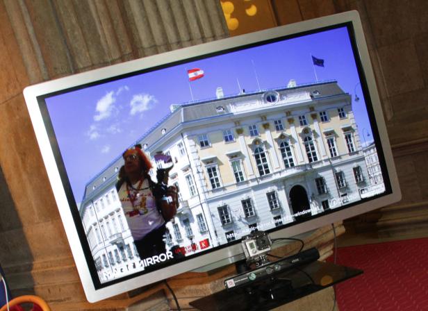 Ein Bildschirm zeigt einen Mann vor dem Palais Liechtenstein in Wien.