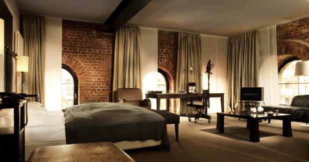 Ein Hotelzimmer mit freiliegendem Backstein, einem Bett und einem Schreibtisch.