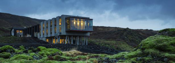 Ein modernes Hotelgebäude steht in einer moosbewachsenen Landschaft.
