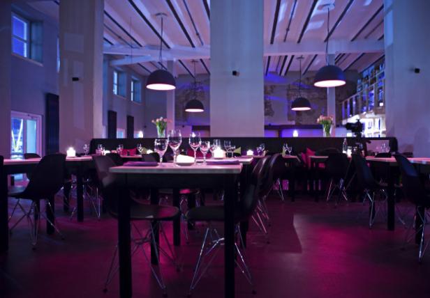 Ein Innenraum eines Restaurants mit Tischen, Stühlen und gedämpfter Beleuchtung.