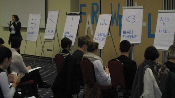 Eine Frau präsentiert vor Publikum Flipcharts mit Aufschriften wie „Highlight“ und „LOL“.