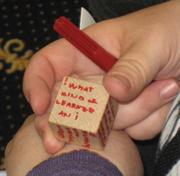 Eine Person hält einen Holzklotz mit der Aufschrift „What kind of learner am I?“ in der Hand.