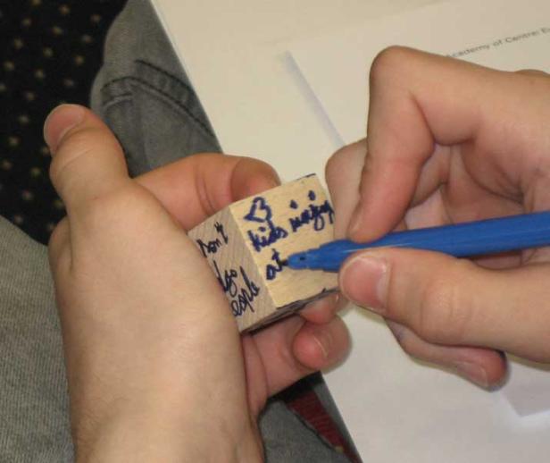 Eine Person beschriftet einen Holzklotz mit einem blauen Stift.