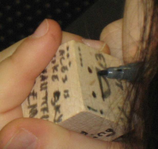 Eine Person beschriftet einen Holzklotz mit einem Stift.