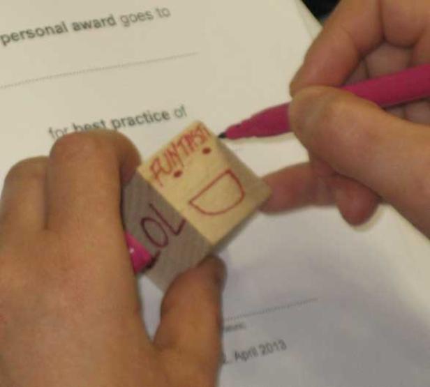 Eine Person bemalt einen Holzklotz mit den Aufschriften „Fun Times“ und „LOL“.