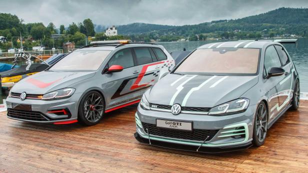 Zwei graue VW Golf GTI Modelle mit auffälligen Designelementen stehen auf einem Holzsteg.