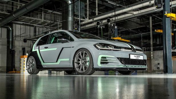 Ein grauer VW Golf GTI Aurora mit mintgrünen Akzenten in einer Werkshalle.