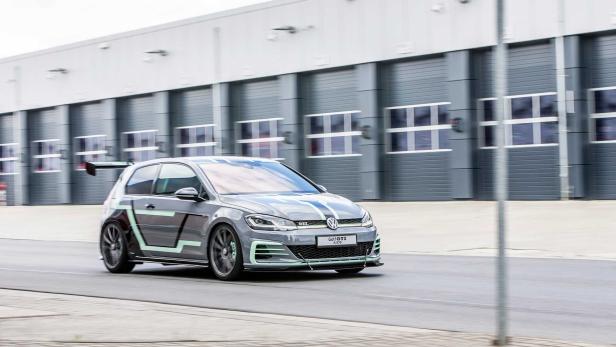 Ein grauer VW Golf GTI mit auffälligen, mintgrünen Akzenten fährt auf einer Straße.