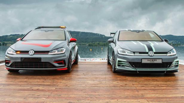 Zwei graue VW Golf GTI-Modelle stehen auf einem Holzsteg vor einem See.