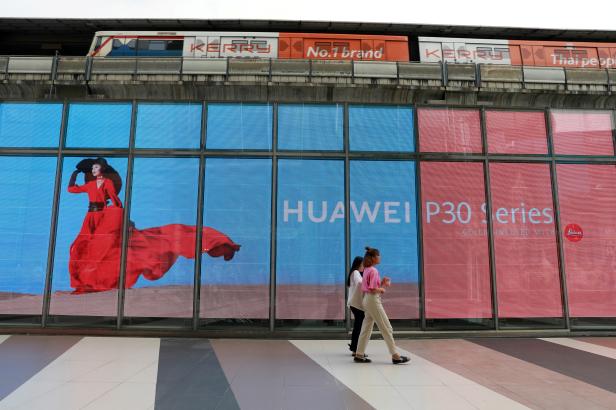 FILE PHOTO: Women walk past a Huawei P30 advertising LED board at a shopping centre in Bangkok