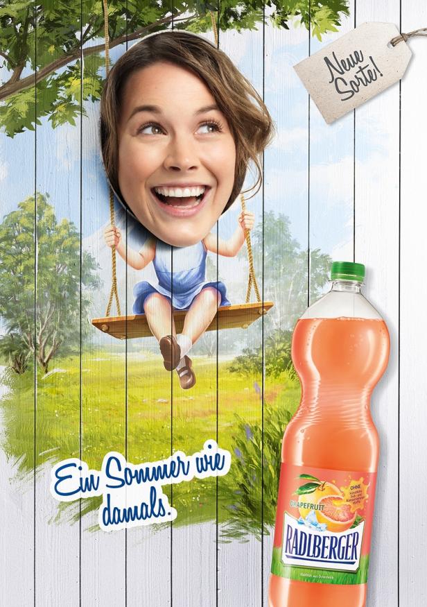 Radlberger - Kampagne - Sujet 1 - Ortner&Weihs Eine Frau schwingt auf einer Schaukel vor einer gemalten Sommerkulisse, daneben eine Flasche Radlberger Grapefruit.