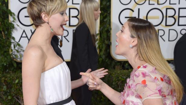 Jennifer Lawrence und Drew Barrymore gestikulieren auf dem roten Teppich.