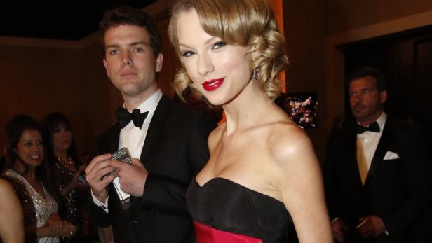 Taylor Swift posiert mit einem Mann im Smoking auf einer Veranstaltung.