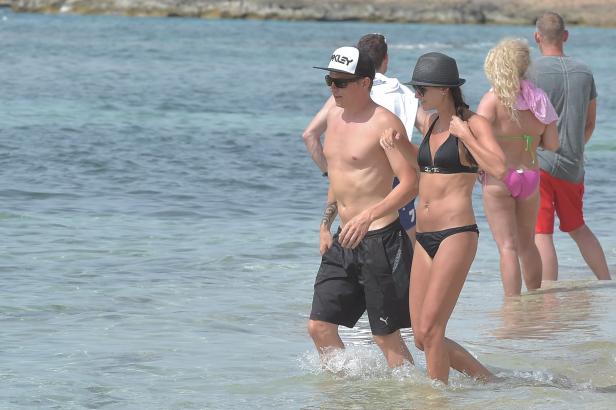 Ein Paar geht am Strand durch das flache Wasser.