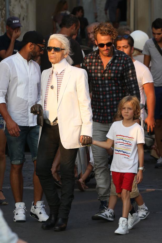 Karl Lagerfeld mit Begleitern auf einer Straße.