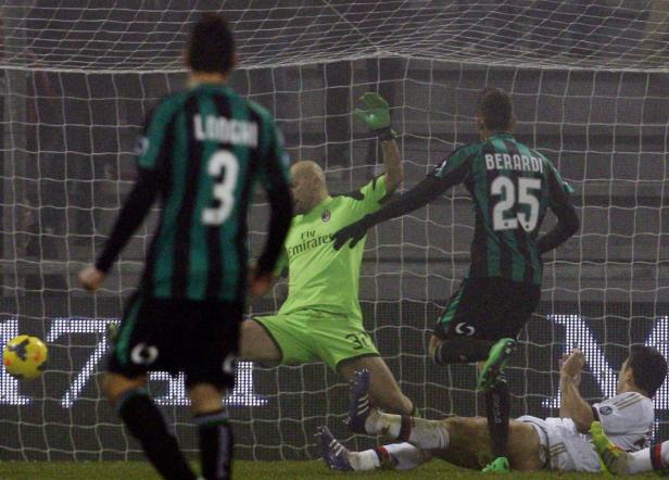 Ein Fußballtorwart wehrt einen Schuss ab, während andere Spieler zusehen.