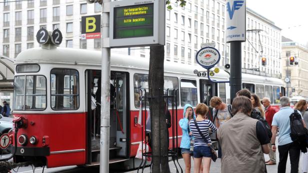 Eine rote und weiße Straßenbahn der Linie 22 an einer Haltestelle in Wien.