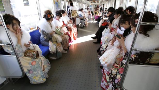 Frauen in Kimonos fahren mit der Bahn.