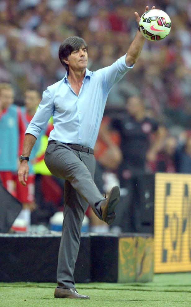 Joachim Löw hält einen Fußball hoch und hebt ein Bein.