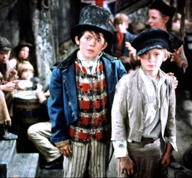 Zwei Jungen in historischer Kleidung stehen vor einer Gruppe von Kindern.