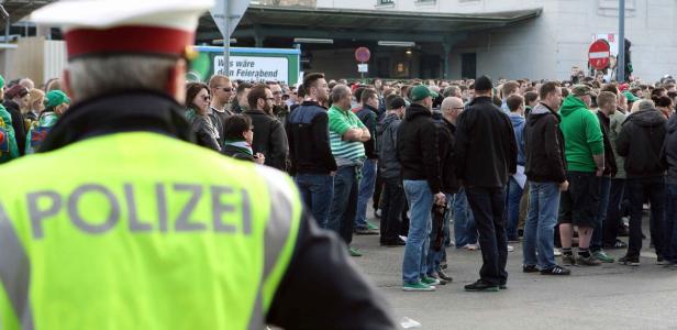Ein Polizist steht vor einer Menschenmenge.