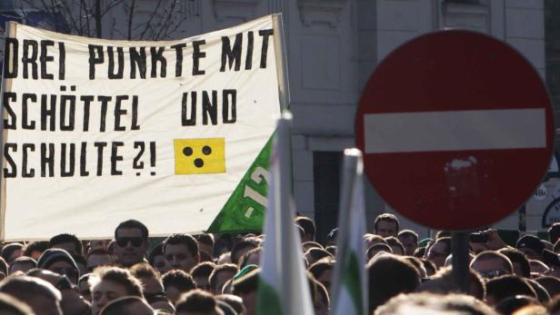 Eine Menschenmenge demonstriert mit einem Transparent, auf dem „Drei Punkte mit Schöttel und Schulte?!“ steht.