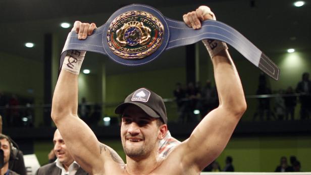 Ein Boxer hält seinen Europameisterschaftsgürtel hoch.