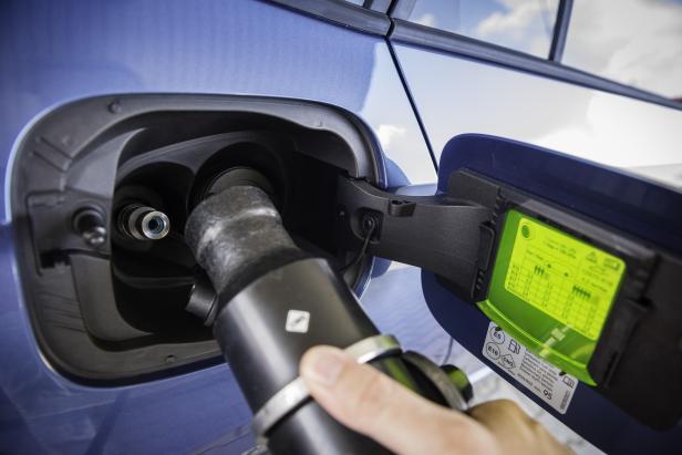 Eine Hand betankt ein blaues Auto mit Erdgas (CNG).