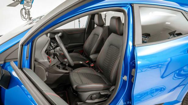 Innenraum eines blauen Autos mit schwarzen Ledersitzen und roten Ziernähten.
