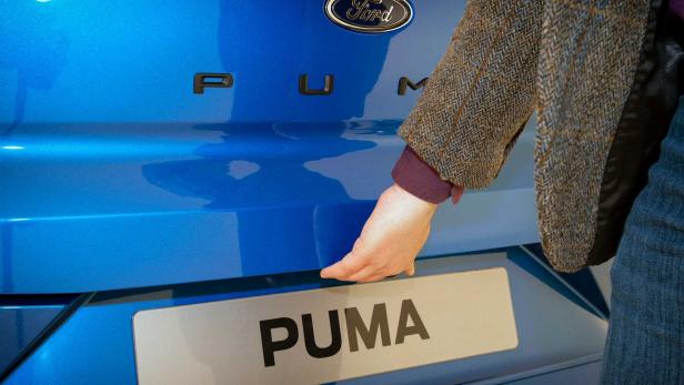 Eine Person öffnet die Heckklappe eines blauen Ford Puma.