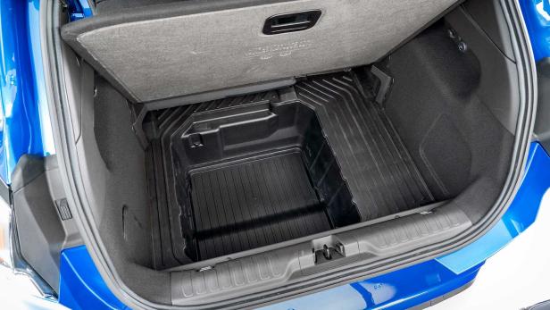 Der offene Kofferraum eines blauen Autos mit einer schwarzen Kunststoffwanne.