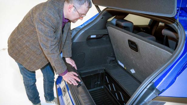 Ein Mann beugt sich über den Kofferraum eines blauen Ford Puma.