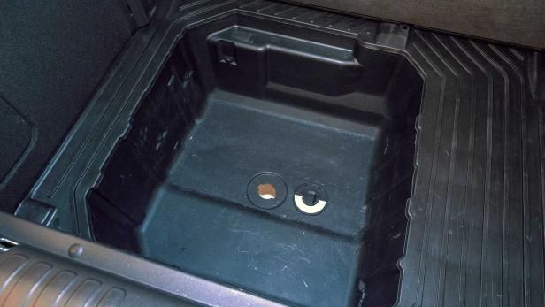 Ein leerer, schwarzer Stauraum im Kofferraum eines Autos.