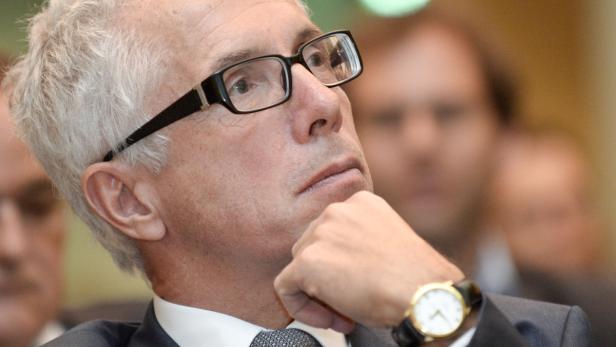 Ein Mann mit Brille und Anzug blickt nachdenklich nach oben.